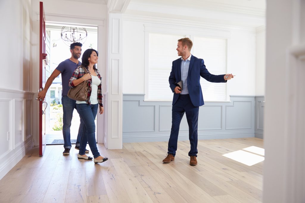 man in business suit showing a man and woman around an empty house realtor real estate agent home open house property