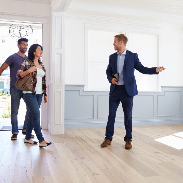 man in business suit showing a man and woman around an empty house realtor real estate agent home open house property